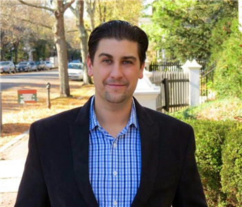 male employee wearing a blue plaid shirt with a black jacket