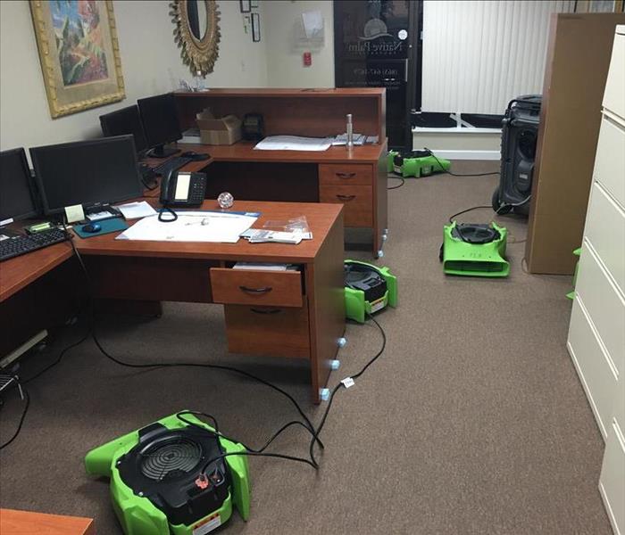 green air movers drying floor in office with desks