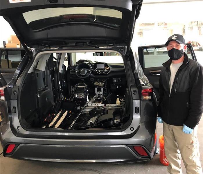 Worker standing by opened black SUV, cleaned and fresh