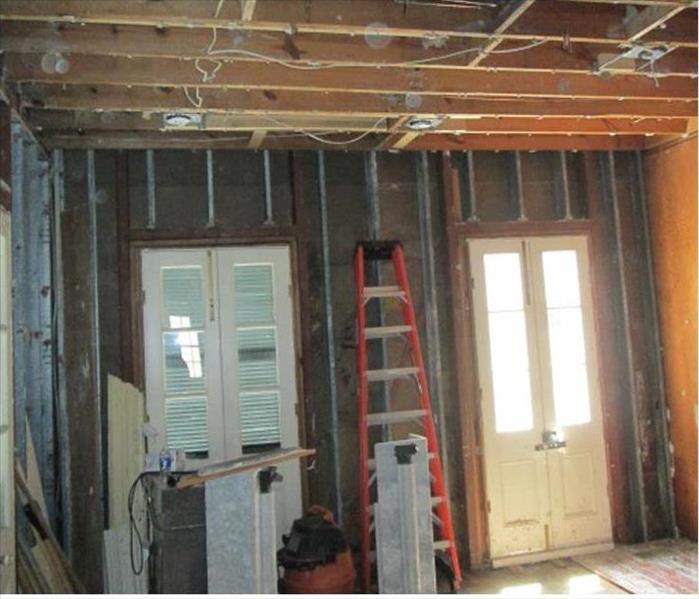 stripped walls and ceiling panels in this room, ladder against the wall