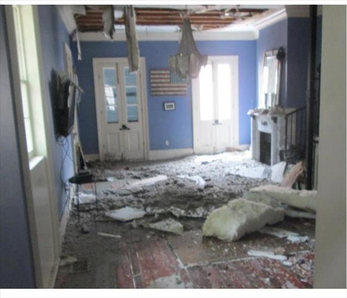 ripped ceiling showing joists, insulation and debris on the floor