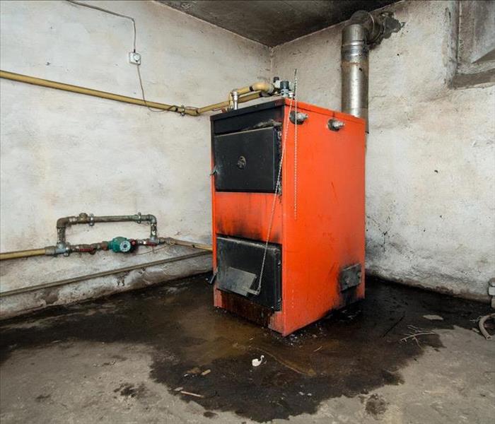 red furnace, leaking and dirty black in a basement